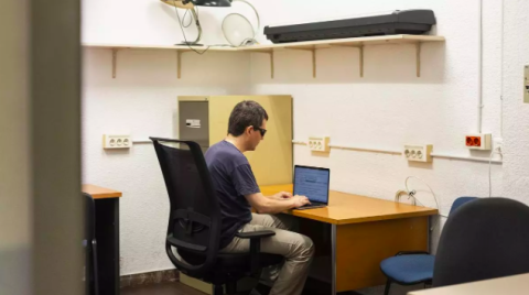 la imagen muestra un joven invidente en su mesa de trabajo